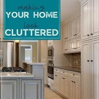 cream kitchen cabinets with gray island-text reads: 5 sneaky things making your home look cluttered