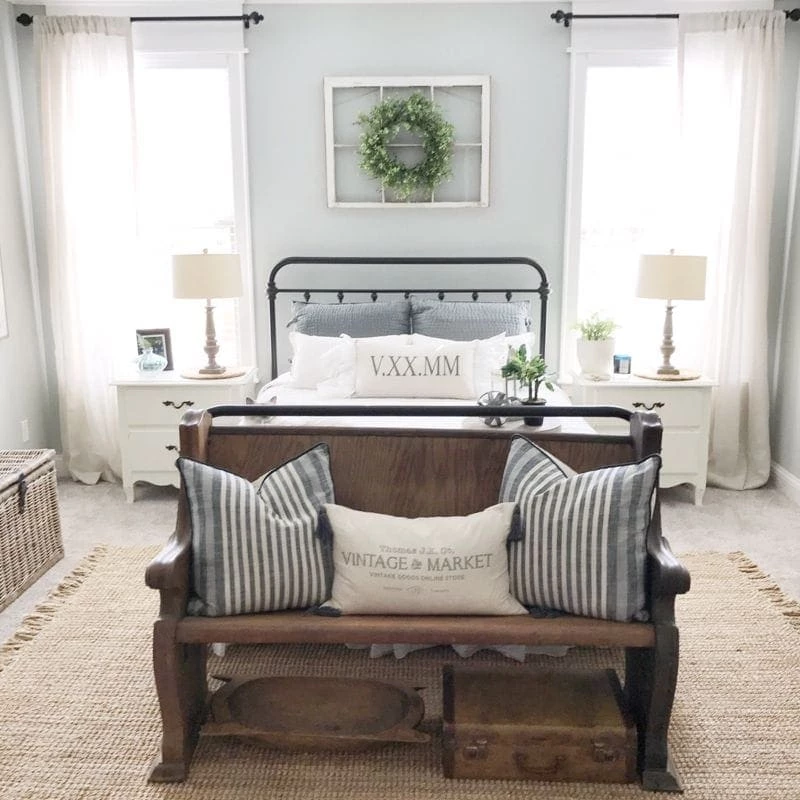 classic farmhouse style bedroom with a black metal bed frame, woven rug, and neutral color tones. 