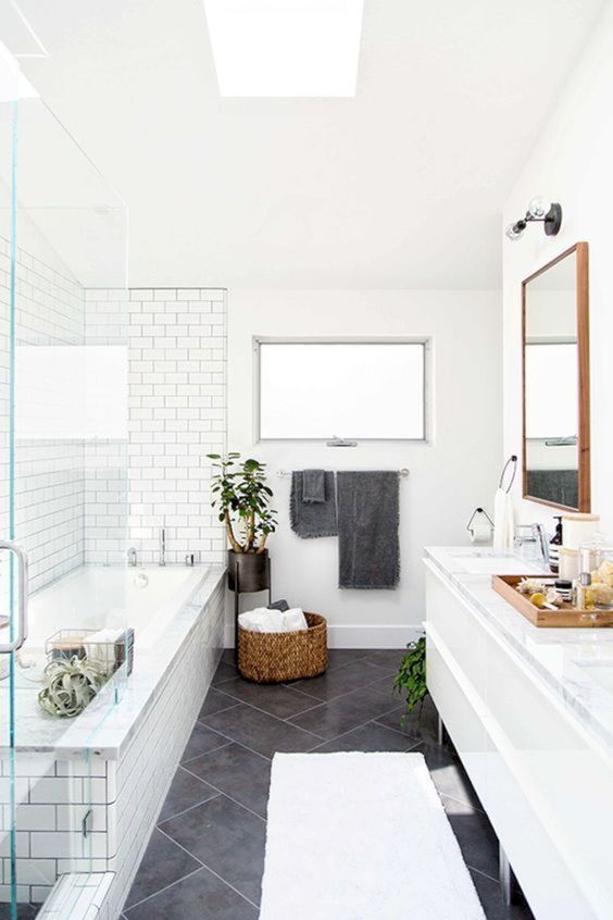 a Scandinavian farmhouse style bathroom with white and grey tiles, a basket for storage and potted plants