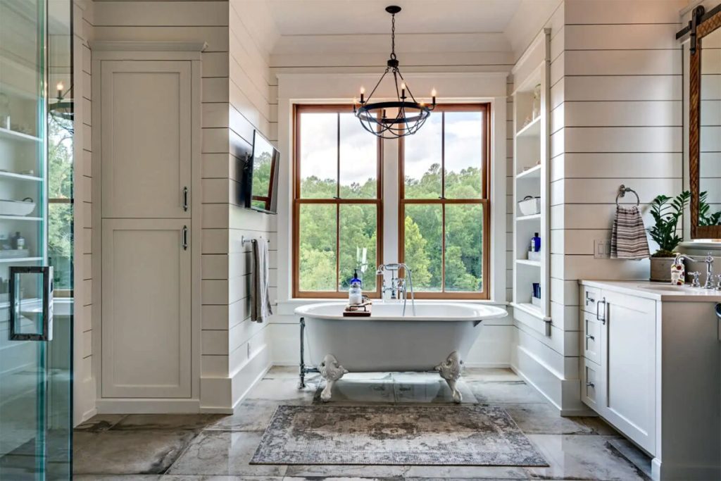 vintage style Claw-Foot Tub as a Centerpiece in a Modern Farmhouse Bathroom with a bronze chandelier and creamy white shiplap for a modern farmhouse look.