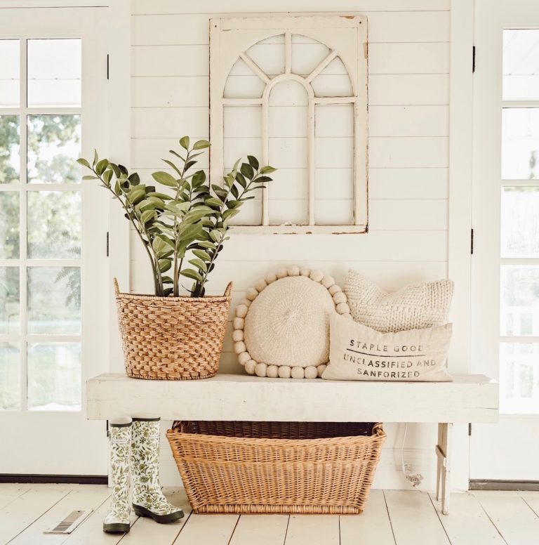 small home entryway decorated with farmhouse cottage syle with a plant in basket, bench, pillows, and ladies rainboots