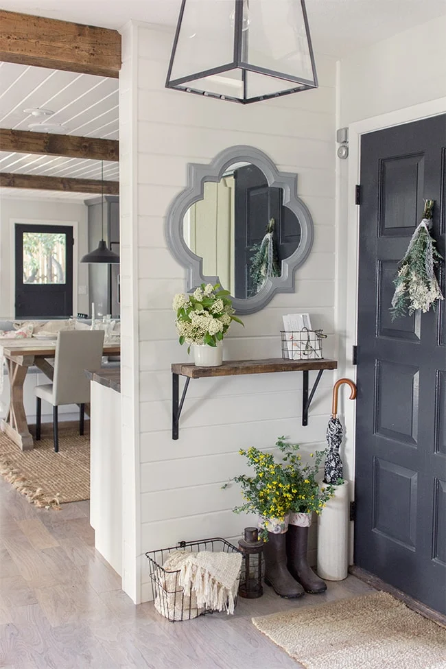 Shabby chic entry with shelf ledge providing space for mail and vase of flowers with mirror  on wall