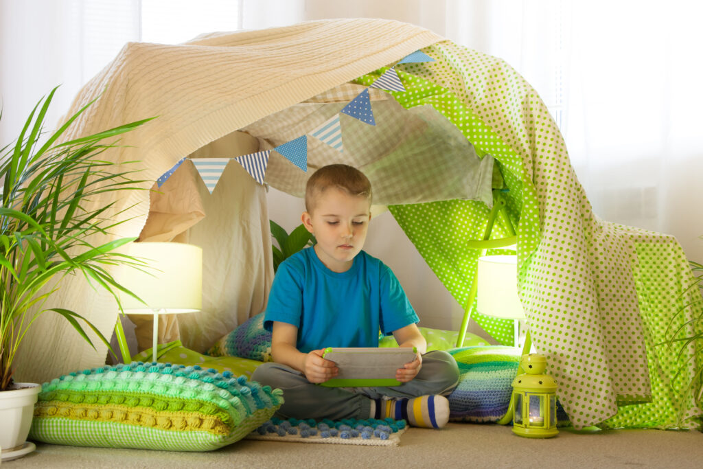 Boy reading under a blanket fort